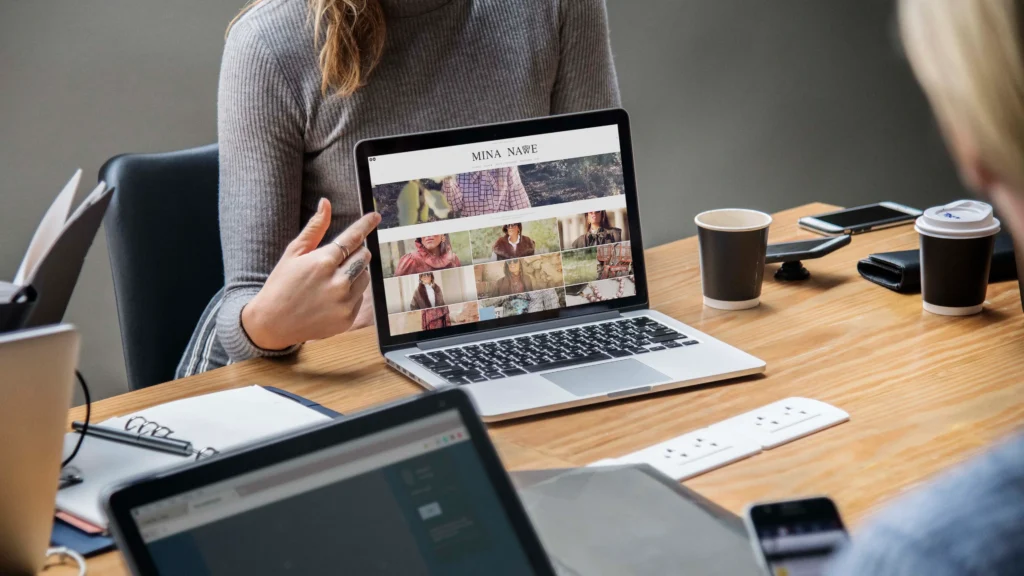 Persona mostrando una web autogestionable en WordPress desde un portátil durante una reunión de trabajo